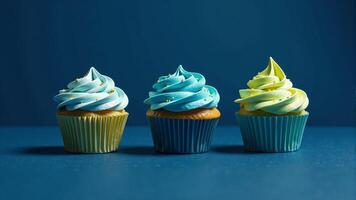Three Cupcakes With Blue And Yellow Frosting photo