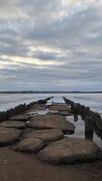 An old wooden destroyed bridge on a frozen river, spring ice melting on the river. photo