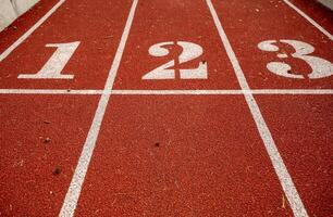 Red running track in stadium, with numbers at the start one, two, three, the running track is deep red. Sport recreation. Helthy lifestyle concept. High quality photo