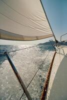 waves crash against the side of a sailing boat traveling at speed, splashes glow in the sun, burning in the background, the glare of the sun on the water photo