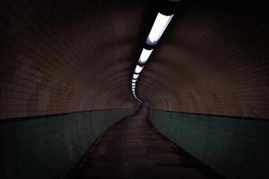 Empty pedestrian tunnel with artificial lights and tiled walls photo