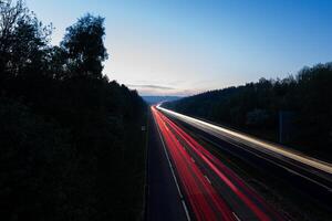 Highway with light trails at dusk showing commuting traffic photo