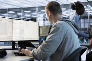 IT engineer looking at PC screen, working in network security data center, ensuring optimal performance. Man supervising server hub, monitoring energy consumption across rigs photo