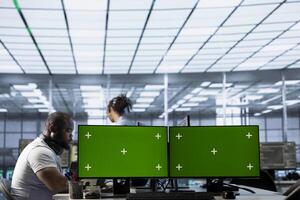 Data center employees using isolated screen multi monitor PC setup to write disaster recovery plans ensuring minimal downtime. Server farm engineers use chroma key computer to monitor performance photo