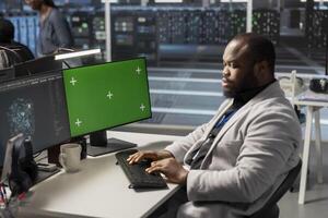 Data center engineer analyzing software logs metrics on green screen mockup PC, optimizing storage systems. Server farm IT expert inspecting resource utilization on chroma key isolated screen computer photo