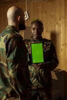 Team of soldiers at shooting range doing training designed to increase safety and survivability in combat, watching instructional videos on green screen chroma key tablet device photo