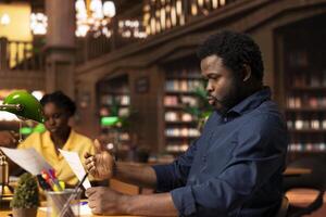 African american college student feels frustrated and overwhelmed with the learning struggles, worried depressed pupil struggling to memorize information from class notes. Academic pressure. photo