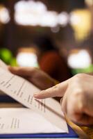 Mature person reading in a public library under a green lamp, deeply focused on studying documents, pursuing senior education and expanding his academic qualifications. Close up. photo