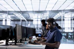 Man in data center workplace hearing songs in headset while using programming languages to build applications. Server hub software developer listening music, debugging code photo