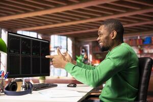 Excited day trader gaining money by selling stocks and maximizing profits, feeling happy. Thrilled african american investor celebrating financial gains earned from stock exchange photo
