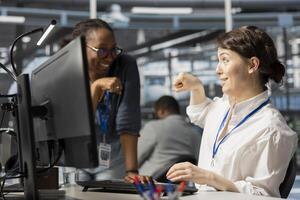 Happy server hub team leader does fist bump with worker after completing operations. Cheerful manager congratulating engineer in data center after checking report showing stable performance indicators photo