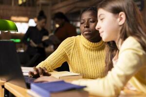 Young teen girls at a study desk attending virtual webinar class, focusing on e learning and academic activity via internet connection. Students chatting with their teacher on live web seminar. photo