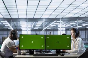 Technicians in data center listening music, optimizing IT infrastructure using green screen PCs. Server room experts wearing headphones upgrading gear with chroma key computers, reducing costs photo