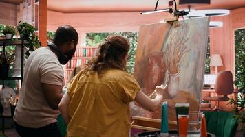 Team of painters collaborating on a rustic masterpiece in art studio, using creative painting techniques with brushes and watercolor paint. Applying multicolored dye on canvas. Camera B. photo