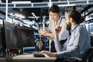 Engineering team doing brainstorming in server hub, using AI powered tech to run simulations. Data center coworkers cooperating, coding algorithms to extract insights from data and automate rigs photo