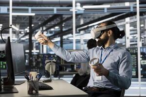 Data center programmer using virtual reality to setup machine learning systems handling information. IT expert using VR headset to train neural networks to improve server farm operations photo
