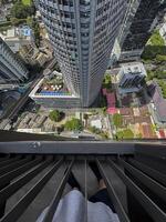 Bangkok, Thailand - November 11, 2024. Tourist high up in a skyscraper, looking down from the big window and capturing the luxurious skyline view on a bustling Thai metropolis. photo