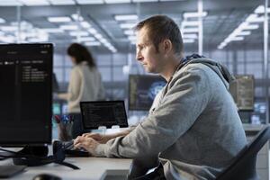 Focused man working in server farm capable of processing vast amounts of data. IT programmer at PC desk typing on keyboard, updating servers controlling network resources photo