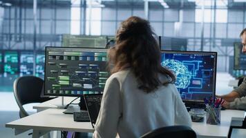 IT employee programming in AI server farm housing advanced equipment used for machine learning training. Admin running code on laptop to upgrade artificial intelligence rigs, camera A photo
