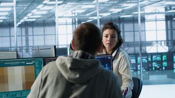 Engineer in server room chitchatting with colleague while making AI generating videos software. IT employee and coworker talking while building artificial intelligence diffusion model app, camera A photo