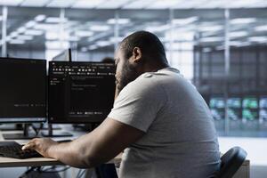 Fatigued engineer falling asleep while typing on computer in server hub, monitoring data center energy consumption. Sleepy employee struggling to stay awake while inspecting rackmounts photo