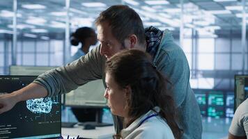 IT team members programming scripts on computer, employing AI machine learning. Software developer and coworker manipulating lines of code for artificial intelligence applications, camera A photo