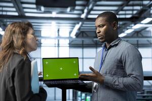 Engineer in data center using chroma key laptop, refining server virtualization strategies. Employees using isolated screen notebook to configure server cluster nodes, maintaining efficient workflows photo