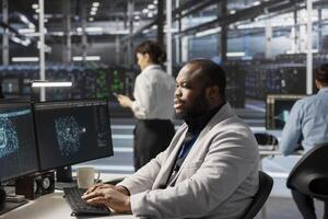 Data center technician in office using artificial intelligence neural networks technology. Man in server room facility using AI programming language on computer to update infrastructure photo