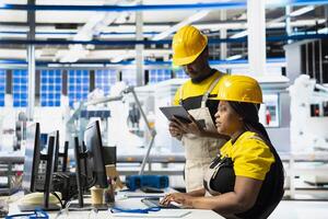 Black team of manufacturing plant employees fixing errors and debugging technical issues, working together in the assembly line of solar panels at the industrial factory. Renewable energy. photo
