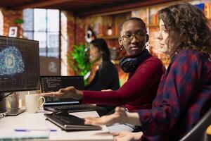 Startup software developers doing brainstorming to do rapid technological advancement in AI industry. African american woman and coworker leveraging machine learning tech to gain competitive edge photo