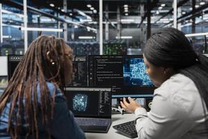 Engineers working together, inspecting neural network data center used for machine learning. Coworkers brainstorming fixes while doing maintenance on server hub to optimize it for AI workloads photo