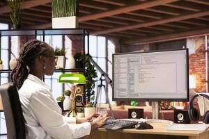 Woman in home office looking at UI on PC display, typing and executing programming code. Coding application UI used by IT developer writing and testing code in modern apartment photo