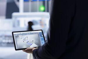 Engineer in photovoltaics factory using tablet to diagnose malfunctioning systems. Solar panels manufacturing plant worker reduces downtime and maintains operational reliability, close up photo