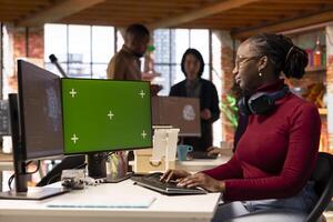 Green screen PC in workspace used by AI researcher working with artificial intelligence technology. Chroma key computer monitor used by employee developing AI systems in tech startup photo