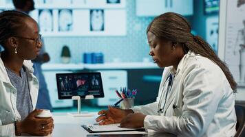 Female general practitioner examining medical data with a patient, fostering interaction and trust during expert consultation focused on wellness. African american girl asks for advice. Camera A. photo