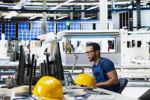 Male engineer using pc setup to oversee solar panel plant assembly lines, troubleshooting photovoltaic system to manage seamless production line with robotic arms. Renewable energy. photo