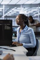 System administrator in data center managing and optimizing IT infrastructure using network management skills. African american server room worker upgrading equipment, reducing operational costs photo