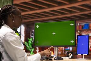 Remote worker in home office using green screen PC and mockup tablet to work on job tasks. Teleworker using chroma key computer monitor and isolated screen device to do job online photo