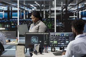 Data center manager supervising engineers implementing AI virtualization to improve resource allocation. Server hub supervisor overseeing employees doing artificial intelligence predictive analysis photo