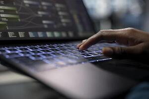 Server room programmer coding on laptop, typing on keyboard, using artificial intelligence to reduce downtime. Close up of worker implementing AI driven solutions for data center using notebook photo