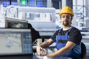 Portrait of photovoltaics factory engineer analyzing data on PC screen, reviewing system health metrics. Solar panels plant worker troubleshooting technical issues at computer desk, diagnosing faults photo