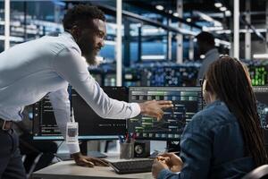 Data center computer scientists setting up machine learning node trees systems handling information. African american workers training neural networks to improve server farm operations photo