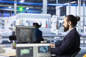 Quality control expert inspecting solar panel specifications on computer screen, ensuring high efficiency. Engineer in photovoltaics factory calibrating robotic arms on PC photo