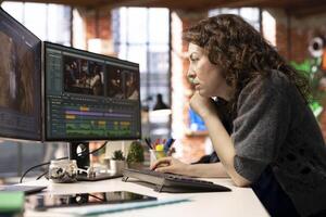 Focused editor woman works on montage in a creative software at agency office, digital media. Filmmaker using dual monitors to edit footage and create content, post production. photo