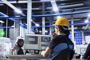 Solar panels plant technical supervisor overseeing real time energy consumption using computer. Photovoltaics factory worker ensuring optimal use of resources in solar panel manufacturing photo