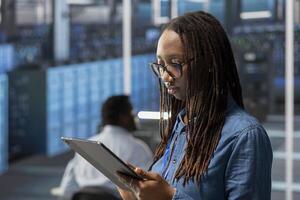 Engineer in server room using tablet to implement and manage data backup solutions to protect against data loss and ensuring efficient recovery processes, identifying and resolving technical issues photo