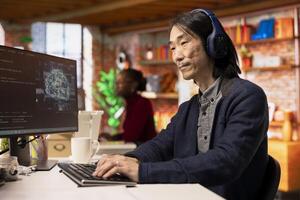 AI startup office chief technology officer listening music while building application. Senior developer wearing headphones while working in artificial intelligence software development agency photo