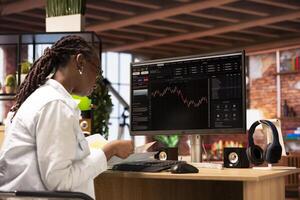 Woman using PC to purchase and sell stocks, reading files, aiming to capitalize on market trends and fluctuations. Investor tracking stock forex trends on computer monitor, looking at documents photo