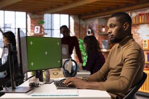 Startup entrepreneur using green screen PC to do research, looking to grow value of company. African american venture business manager using mockup computer, building innovative growth strategy photo