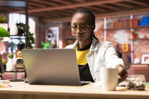 Teleworker using laptop device in apartment office to write emails. Remote employee in home workspace typing on notebook keyboard, composing documents in order to deliver project photo